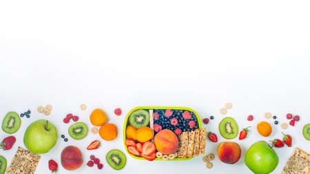 Summertime healthy food concept: Frame with lunch box and various fruits, berries and crunches on...