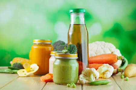 Natural baby food on the wooden background with copy space: jars with vegetable and fruit puree and...