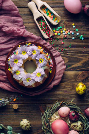 Happy Easter card: painted quail and chicken eggs in natural nest, traditional Easter ring cake...