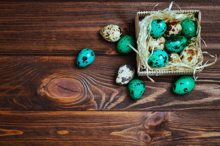 Easter decoration concept: Painted turquoise quail eggs in the box over rustic wooden background with copy space top view, flat layの写真素材