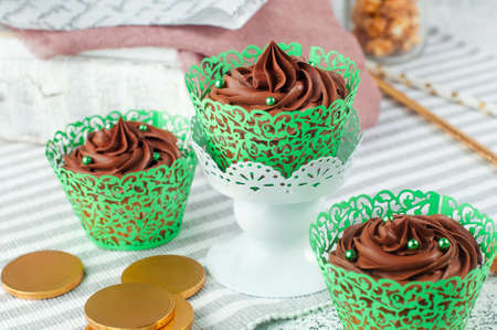 St. Patrick's Day party table: Chocolate cupcakes with green sugar sprinkles and golden coins selective focusの写真素材