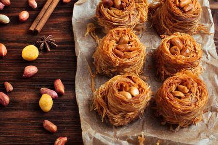 Traditional turkish dessert baklava nest with peanuts on rustic wooden background selective focusの写真素材