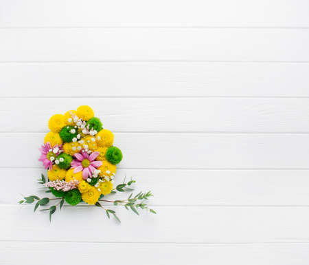 Easter egg made from flowers on white wooden background with copy spaceの写真素材