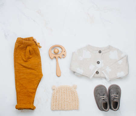 Newborn baby booties, clothing and teether on light marble background with blank space for text. Top view, flat lay.の写真素材