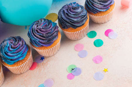 Vanilla cupcakes with galaxy dark whipped cream on party background with blank space for text