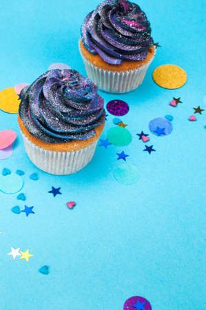 Vanilla cupcakes with galaxy dark whipped cream on party background with blank space for text