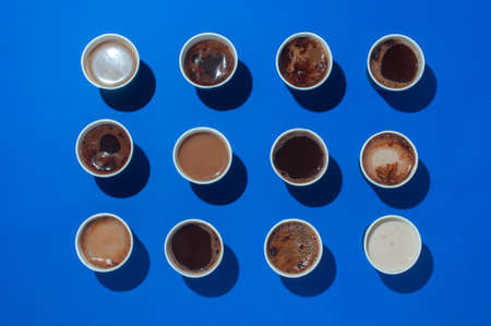 Lots of coffee cups with different types of coffee, cappuccino and macchiatoon on blue background with blank space for text. Top view, lat lay.の写真素材