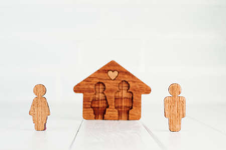Family home concept. Wooden house with figures of man and woman on light background with blank space for text.の写真素材