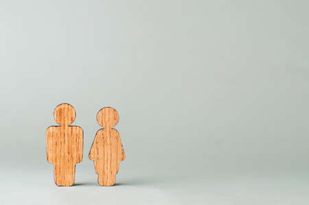 Wooden figures of man and woman on gray background with blank space for text.