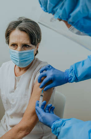 Doctor in protective overall and gloves making   vaccinationの写真素材