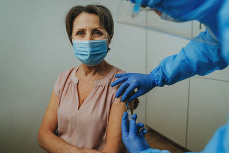 Doctor in protective overall and gloves making  vaccinationの写真素材