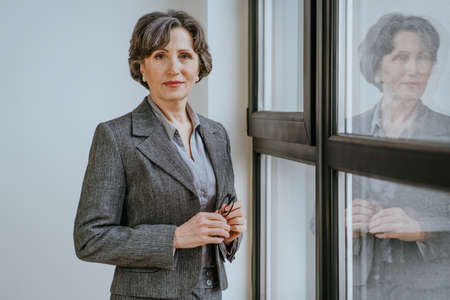 Mature businesswoman looking at camera standing in an officeの写真素材