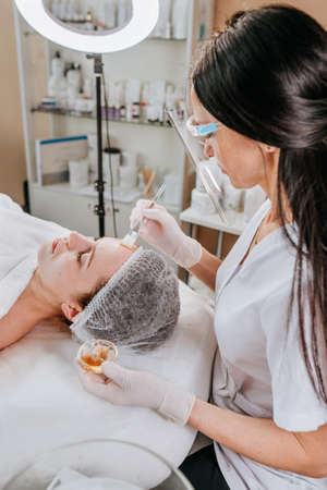 Esthetician or facialist making facial cleansing procedure