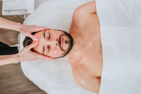 Esthetician or facialist gives a relaxing facial massage to a manの写真素材