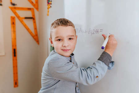 Elementary school student writing on the blackboard by felt-tip in the classroomの写真素材