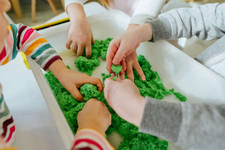 Preschool students playing with kinetic sand in kindergartenの写真素材