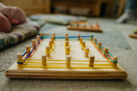 Preschool students playing with geoboard wrapping rubber bands in kindergartenの写真素材