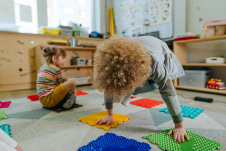 Preschool students having fun time jumping and walking on massage mats