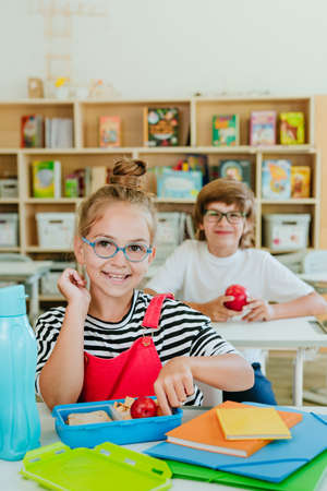 Elementary school students eating from the lunchboxes in the classroomの写真素材