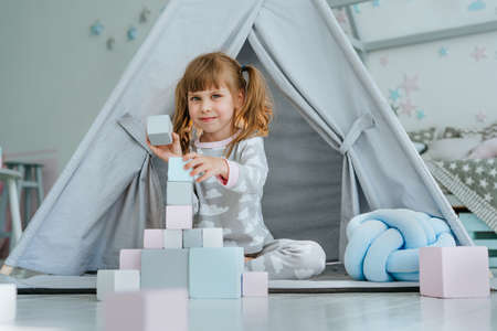 Beautiful little girl playing with wooden toy blocksの写真素材