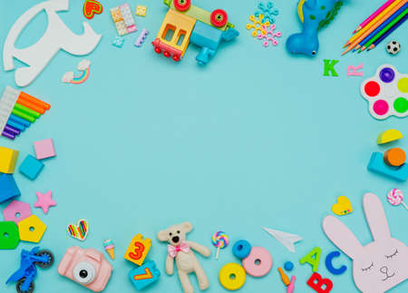 Kids toy background. Variety of plastic and wooden kids toys on blue background with blank space for text. Top view, flat lay.の写真素材