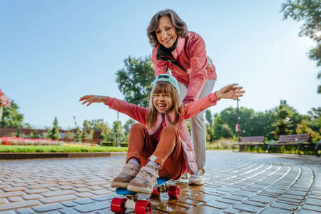 Active happy grandmother and granddaughter having fun time together skatingの写真素材