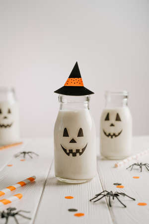 Glass bottles of milk cocktail decorated with jack-o-lantern face and hatの写真素材