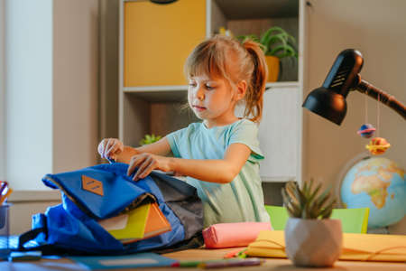 Elementary female student packing backpack for school at home. Selective focus.の写真素材