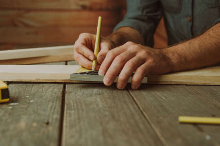 Close up of worker measuring wooden detail on the table. Selective focus.の写真素材