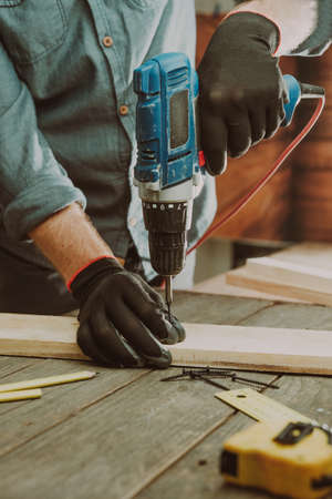Close up of worker using electric scredriver on the table. Selective focus.の写真素材