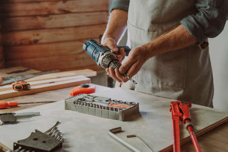 Close up of worker changing a drill for screwdriverの写真素材