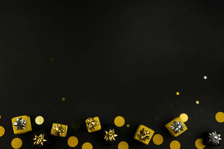 Gift present boxes and confetti on black background with blank space for text. Top view, flat lay.の写真素材