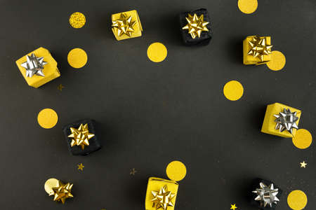 Gift present boxes and confetti on black background with blank space for text. Top view, flat lay.の写真素材