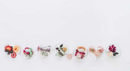 DIY ornaments filled with dried flowers on white wooden background with blank space for text. Christmas tree decor idea. Top view, flat lay. Horizontal panorama banner.の写真素材