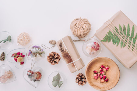 DIY packaging and ornaments filled with dried flowers on white background with blank space for text. Christmas decor idea. Top view, flat lay.の写真素材