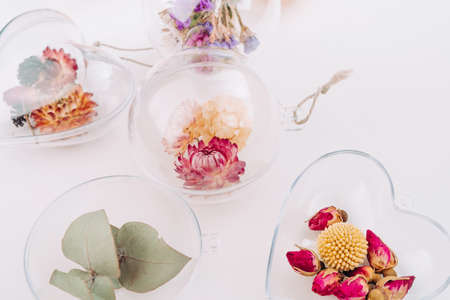DIY ornaments filled with dried flowers on white background with blank space for text. Christmas decor idea. Top view, flat lay.の写真素材