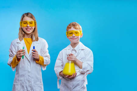 Two schoolchildren with eye glasses holding chemical test tubes and containerの写真素材