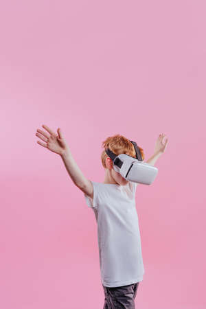 Teenager boy wearing virtual reality device. Studio portrait on pink background with blank space for textの写真素材