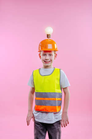 Teenager boy wearing helmet with lamp as idea symbol. Studio portrait on pink background with blank space for textの写真素材