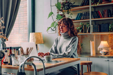 Young woman freelancer working at the vintage style interior cafe using laptop. Selective focus.
