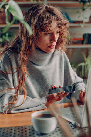Young woman freelancer working at the cafe using laptop and smartphone. Selective focus.
