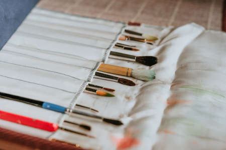 Set of painting brushes in the fabric lying on the table. Art concept. Selective focus.の写真素材