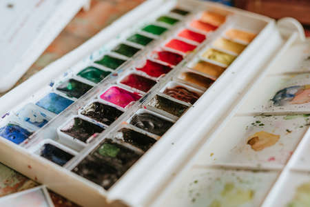 Colorful watercolor paints lying on worktable at artist workshop. Selective focus.の写真素材