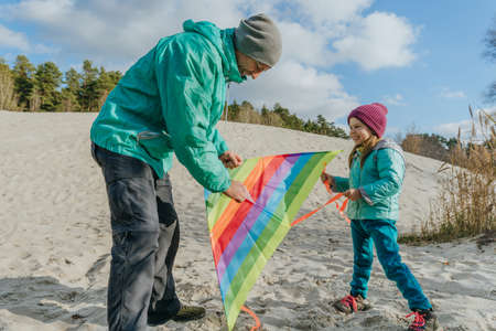 Father with his 5 years old daughter prepairing kite to fly. Happy family activities outdoor....