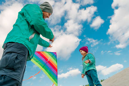 Father with his 5 years old daughter prepairing kite to fly. Happy family activities outdoor....