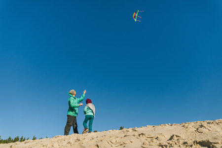 Father with his 5 years old daughter flying a kite on the sand beach. Happy family activities outdoor. Parenthood concept.の写真素材