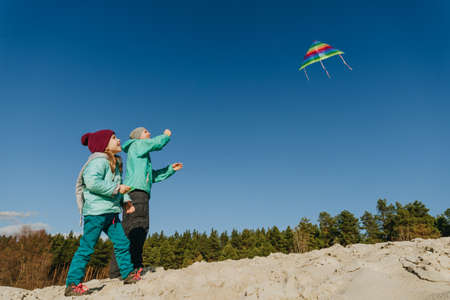 Father with his 5 years old daughter flying a kite on the sand beach. Happy family activities outdoor. Parenthood concept.の写真素材