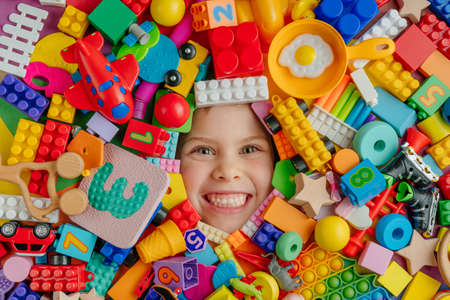 Funny kid lying in a very large quantity of toys. Childhood concept. Top view, flat lay.の写真素材