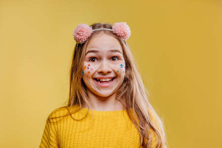Surprised teenage girl with stickers on her face wearing pink fluffy hair hood