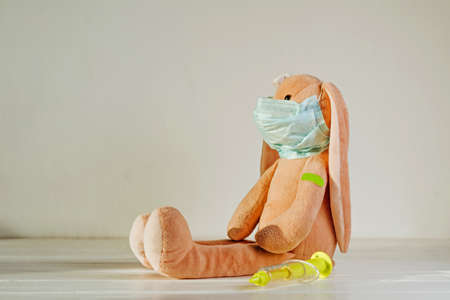 Soft toy bunny with medical tape plaster on the shoulder after injectionの写真素材